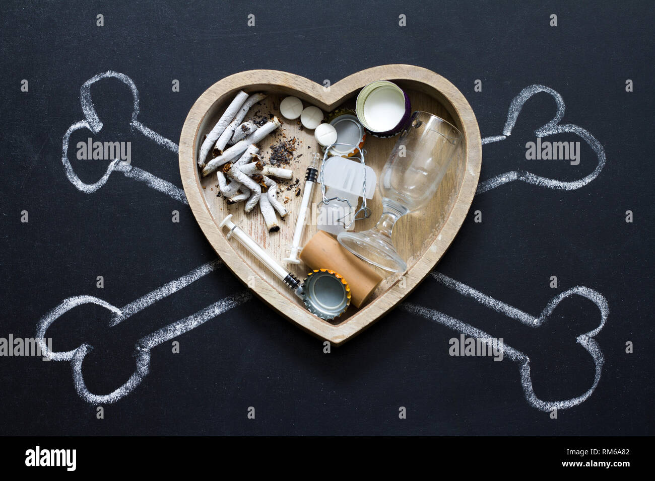 Le sostanze che provocano assuefazione sigarette alcool e droghe nel cuore e nelle ossa simbolo di pericolo Foto Stock