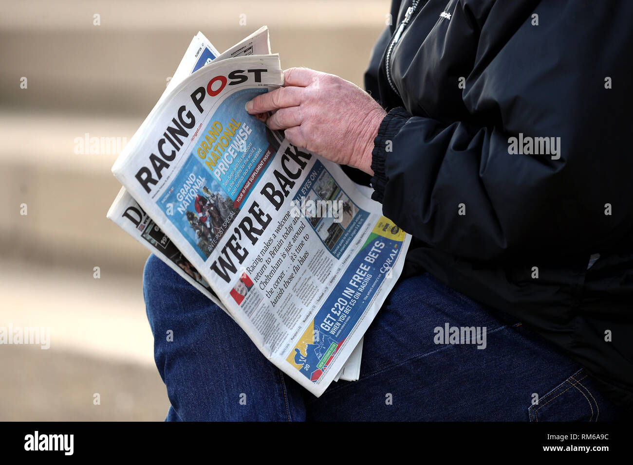 Un racegoer legge il Racing Post con il lato anteriore della pagina headline "siamo indietro' durante i feriti Fantini Fondo Raceday carità a Plumpton Racecourse. Foto Stock