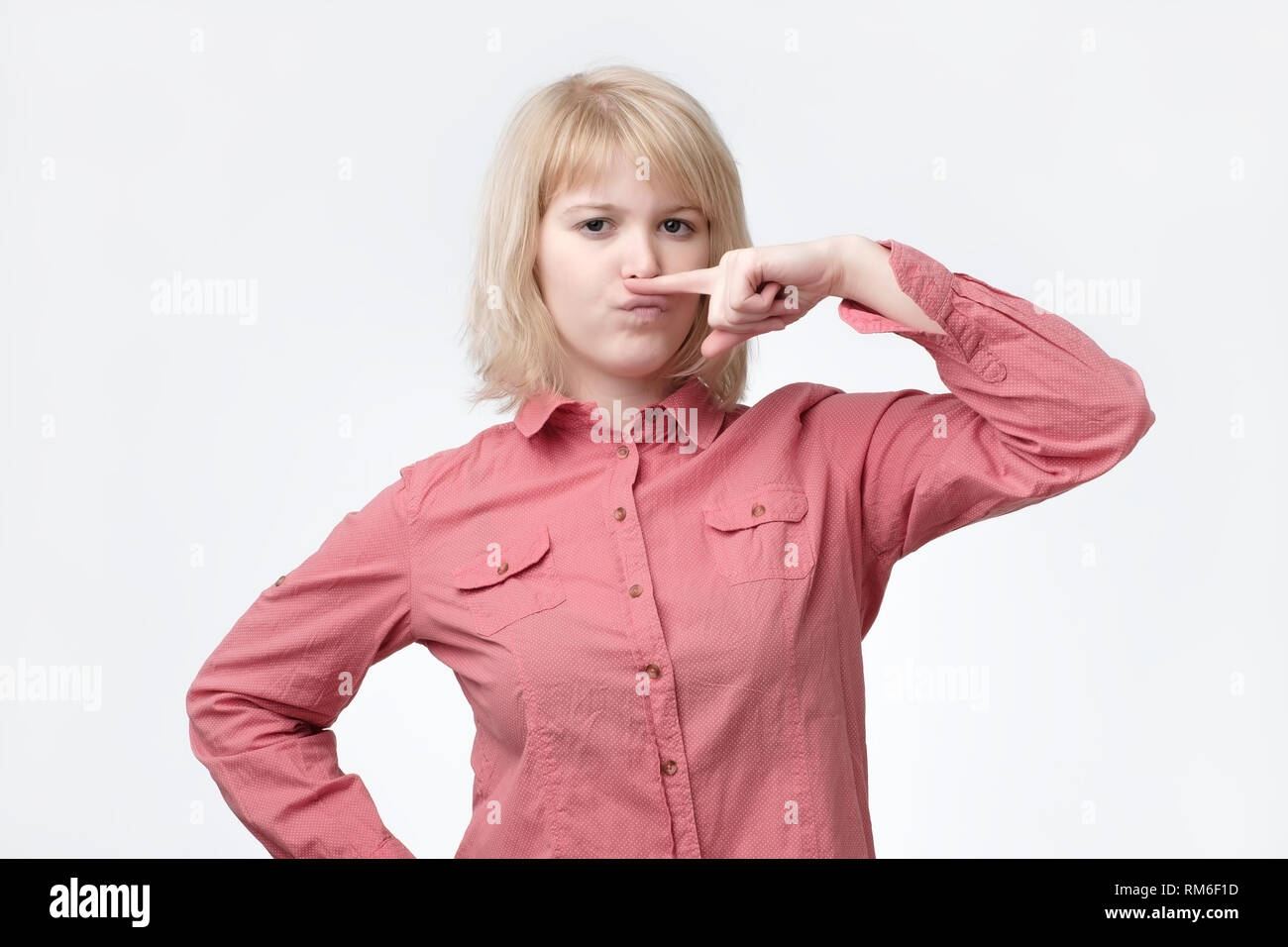 Donna bionda che mostra i baffi con il dito. Ella è sensazione di cattivo odore. Foto Stock