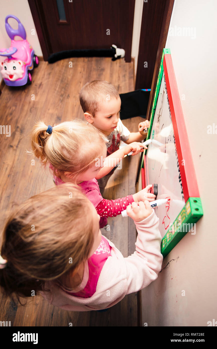 Bambini il disegno di una foto di apprendimento di una lettere giocando insieme utilizzando la lavagna e pennarelli Foto Stock