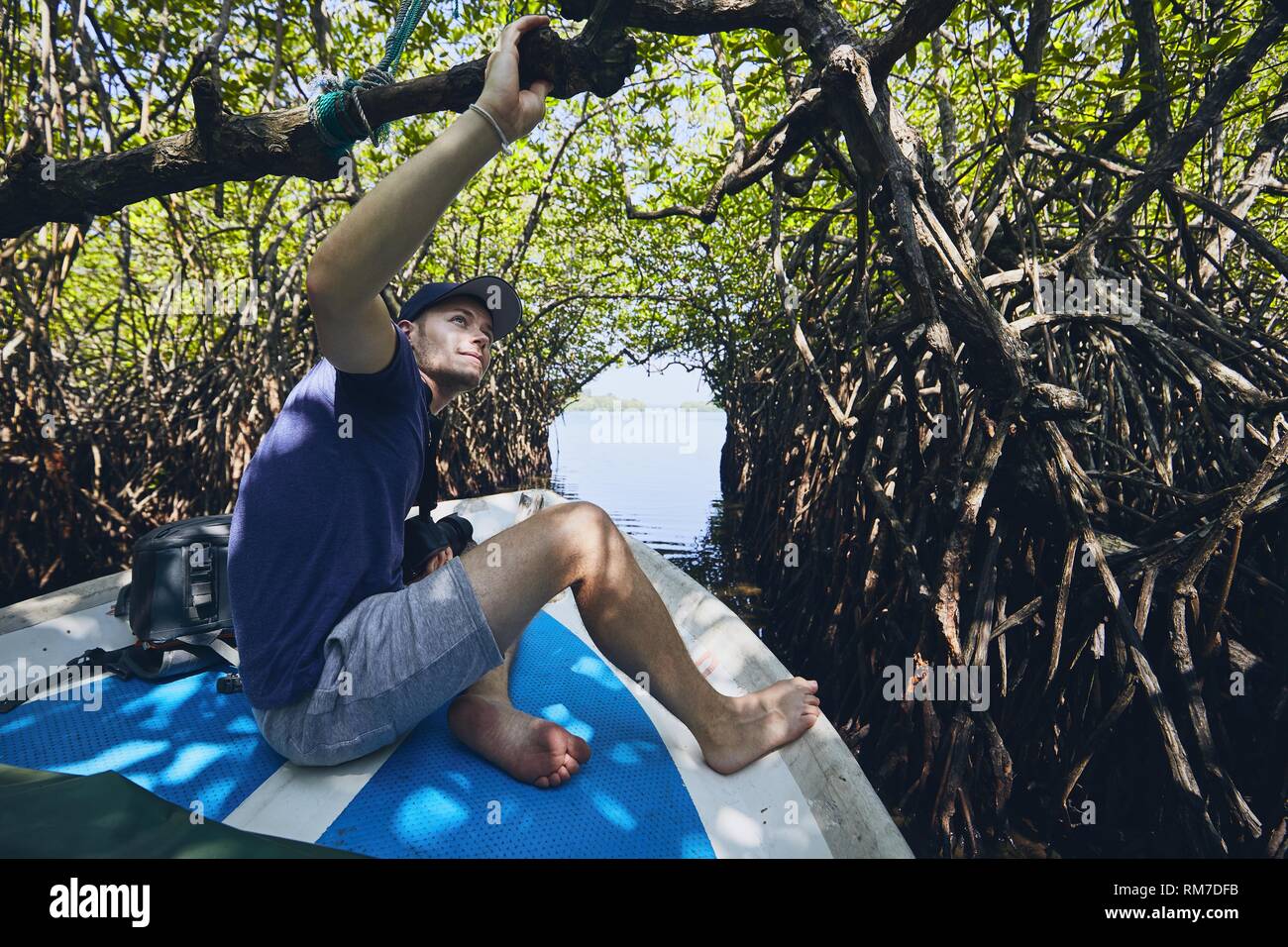 Giovane uomo durante il viaggio in barca attraverso la foresta di mangrovie in Sri Lanka. Foto Stock