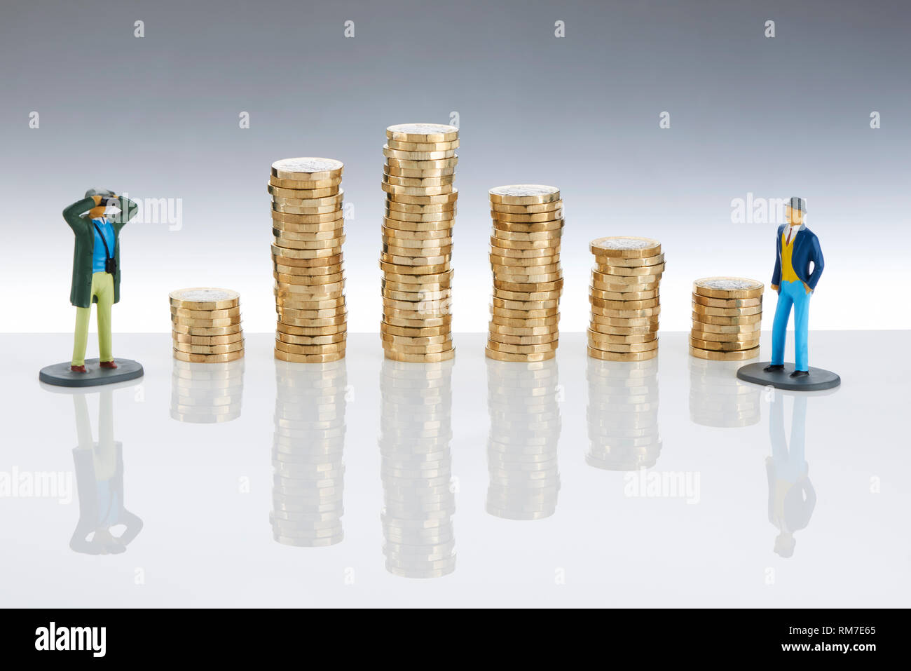 Pile di £ 1 libbre con il modello gli uomini alla ricerca su Foto Stock