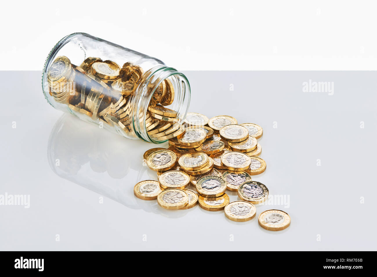 £ 1 monete in caduta da un risparmio di vetro Jar Foto Stock