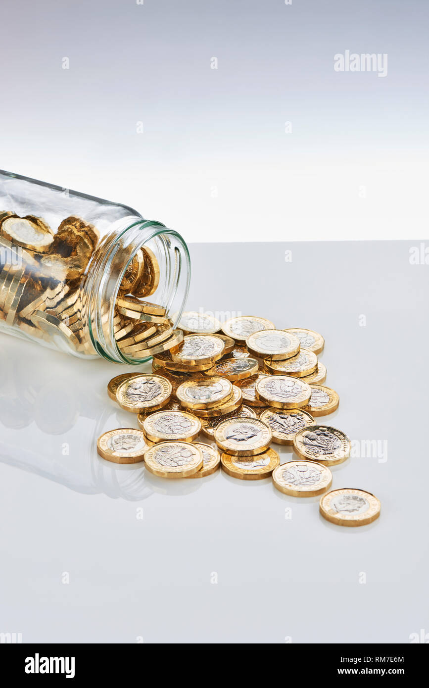 £ 1 monete in caduta da un risparmio di vetro Jar Foto Stock