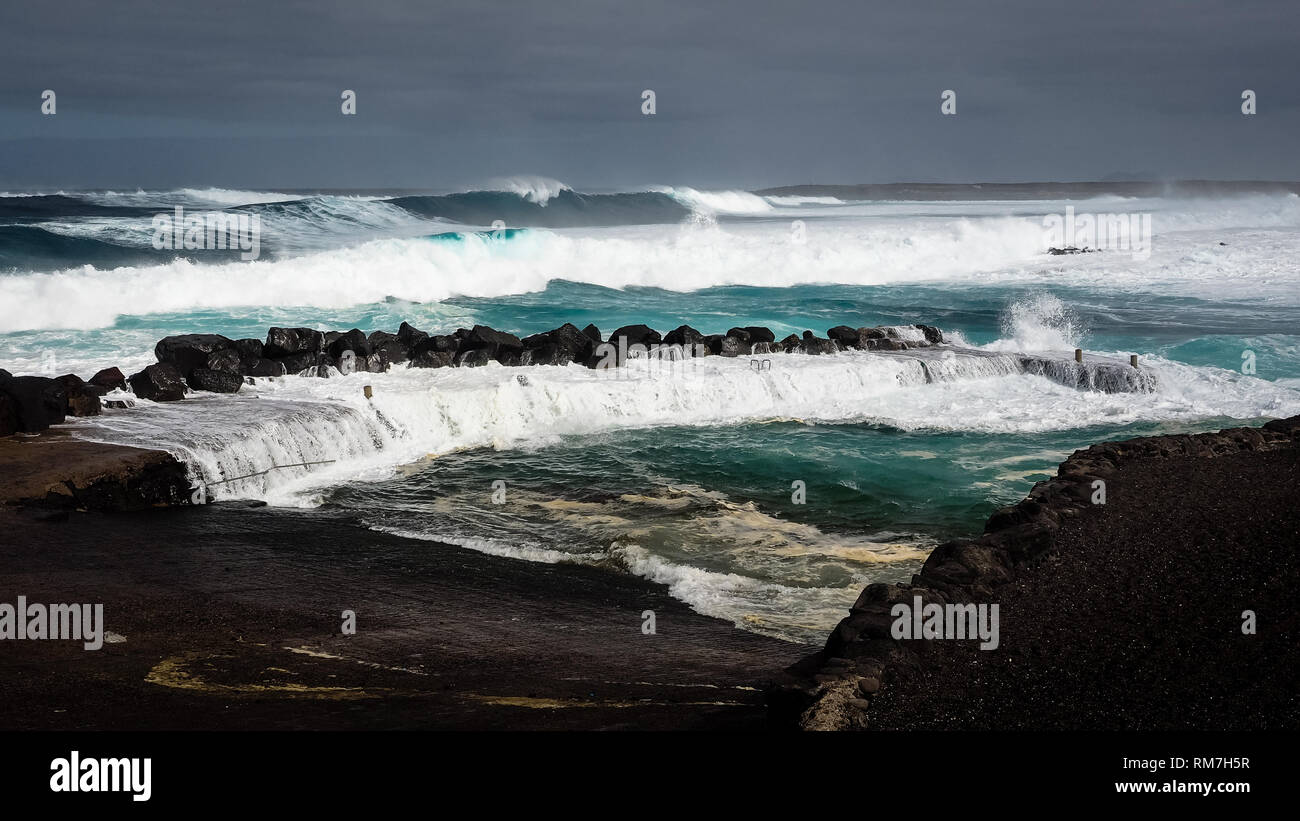 Le onde di saltare sul dock della baia di pesca di La Santa in Lanzarote durante una tempesta. Isole Canarie Foto Stock