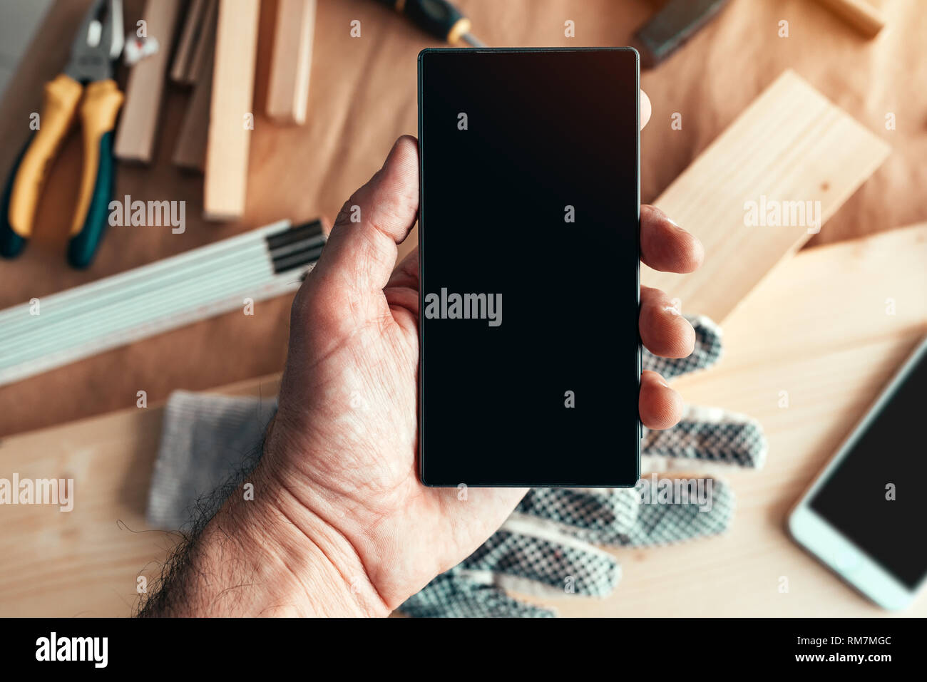 Tuttofare manutentore azienda smartphone con vuoto mock up schermo al di sopra del banco di officina con strumenti Foto Stock
