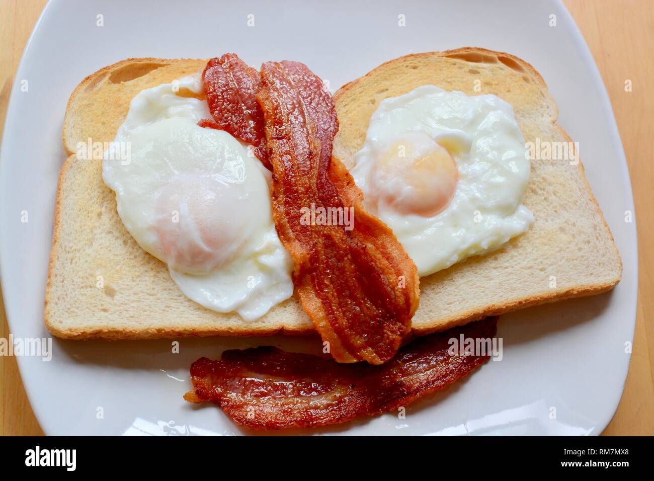 Le uova in camicia su toast bianchi con pancetta Foto Stock