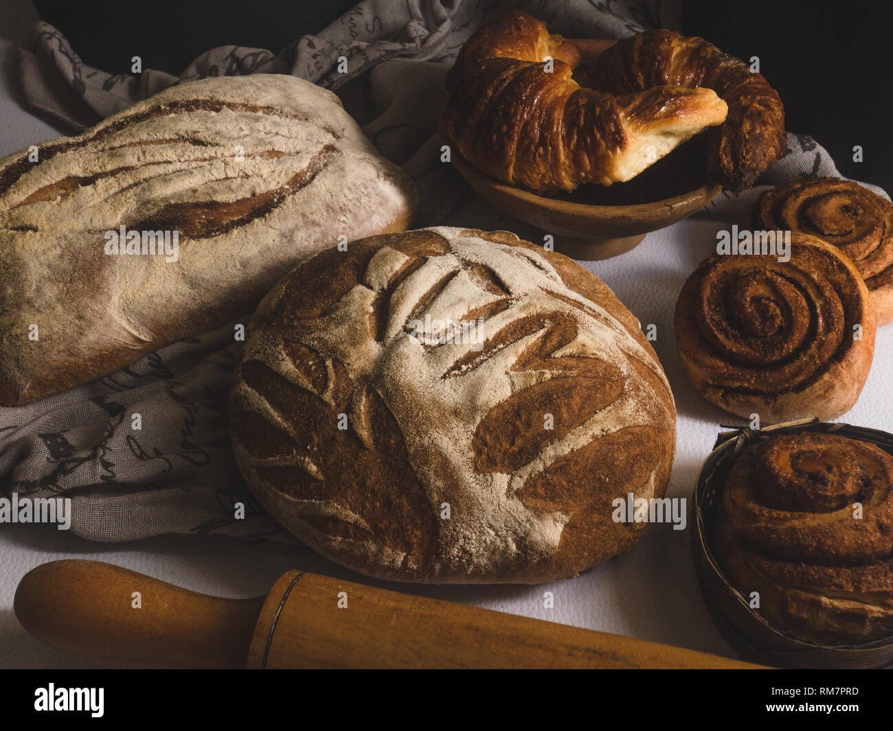 Un Bounty di pane cornetti e panini alla cannella fotografia scuro Foto Stock