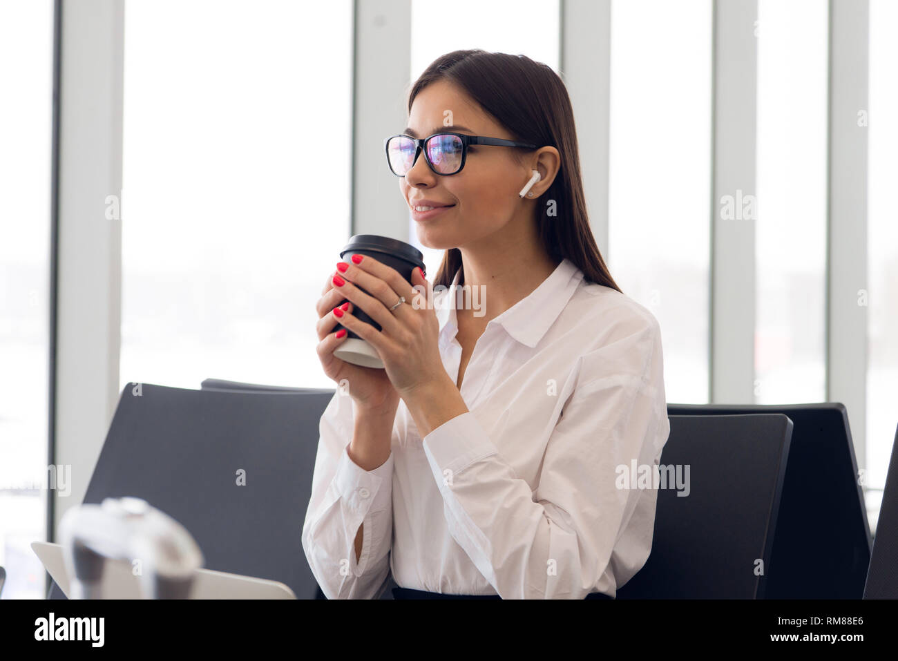 Bella ragazza all aeroporto internazionale di bere il caffè per andare in attesa per il suo volo. Passeggero femmina sul terminale, in interni. Chi viaggia Foto Stock