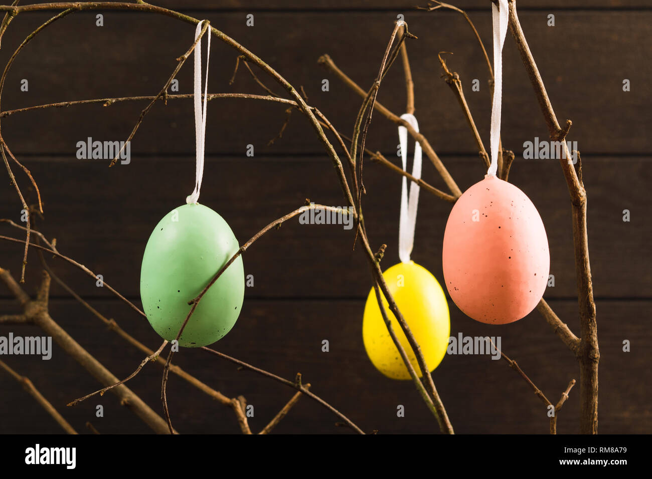 Tre uova di pasqua con rami di legno scuro di sfondo, il fuoco selettivo Foto Stock