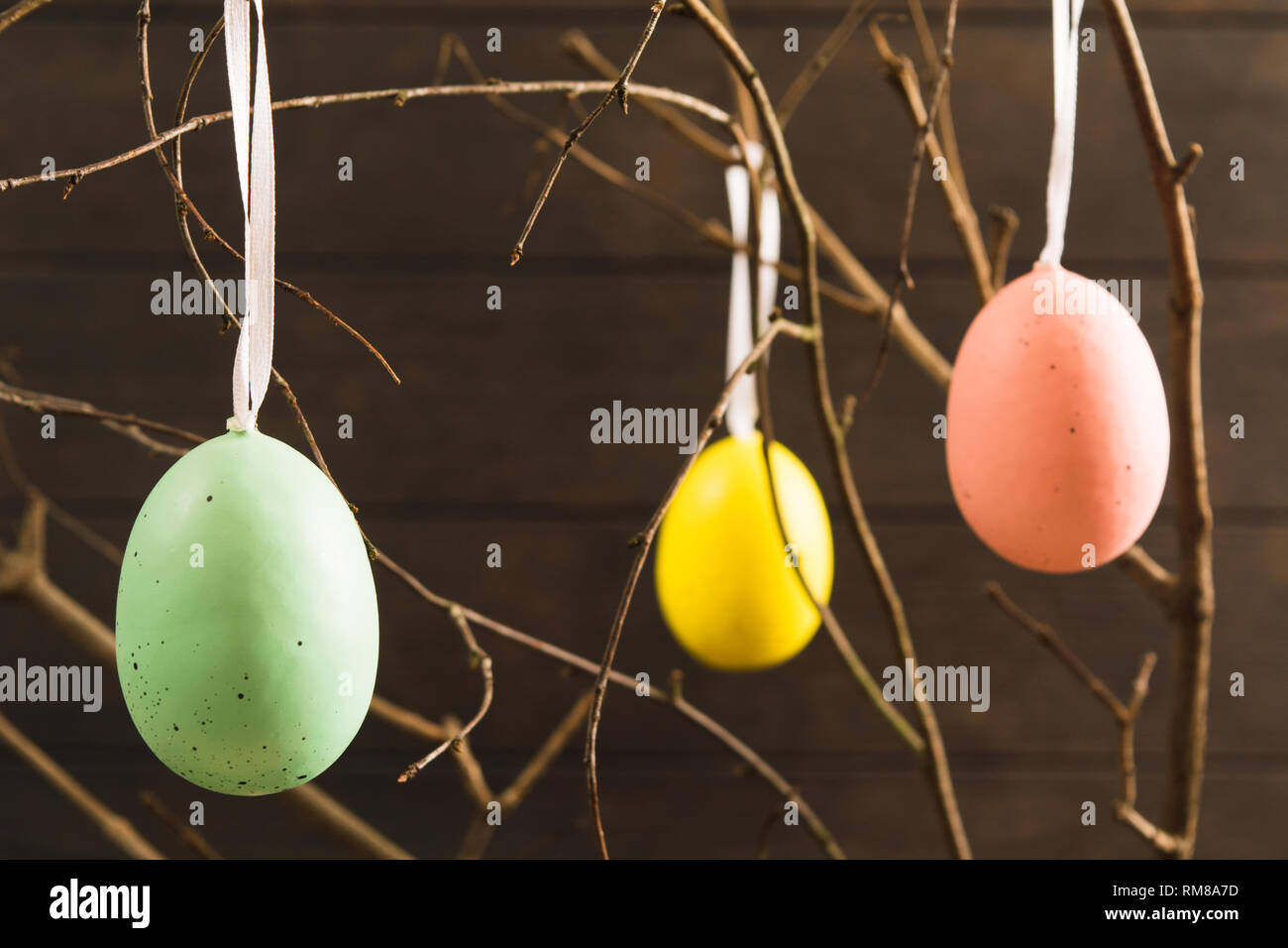 Colorate le uova di pasqua con nastro su albero su sfondo di legno Foto Stock