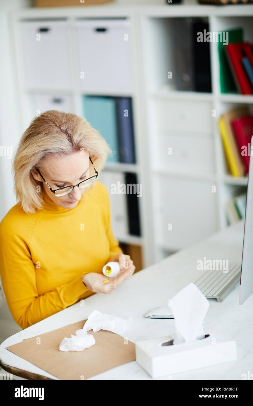 Donna di prendere pillole al posto di lavoro Foto Stock