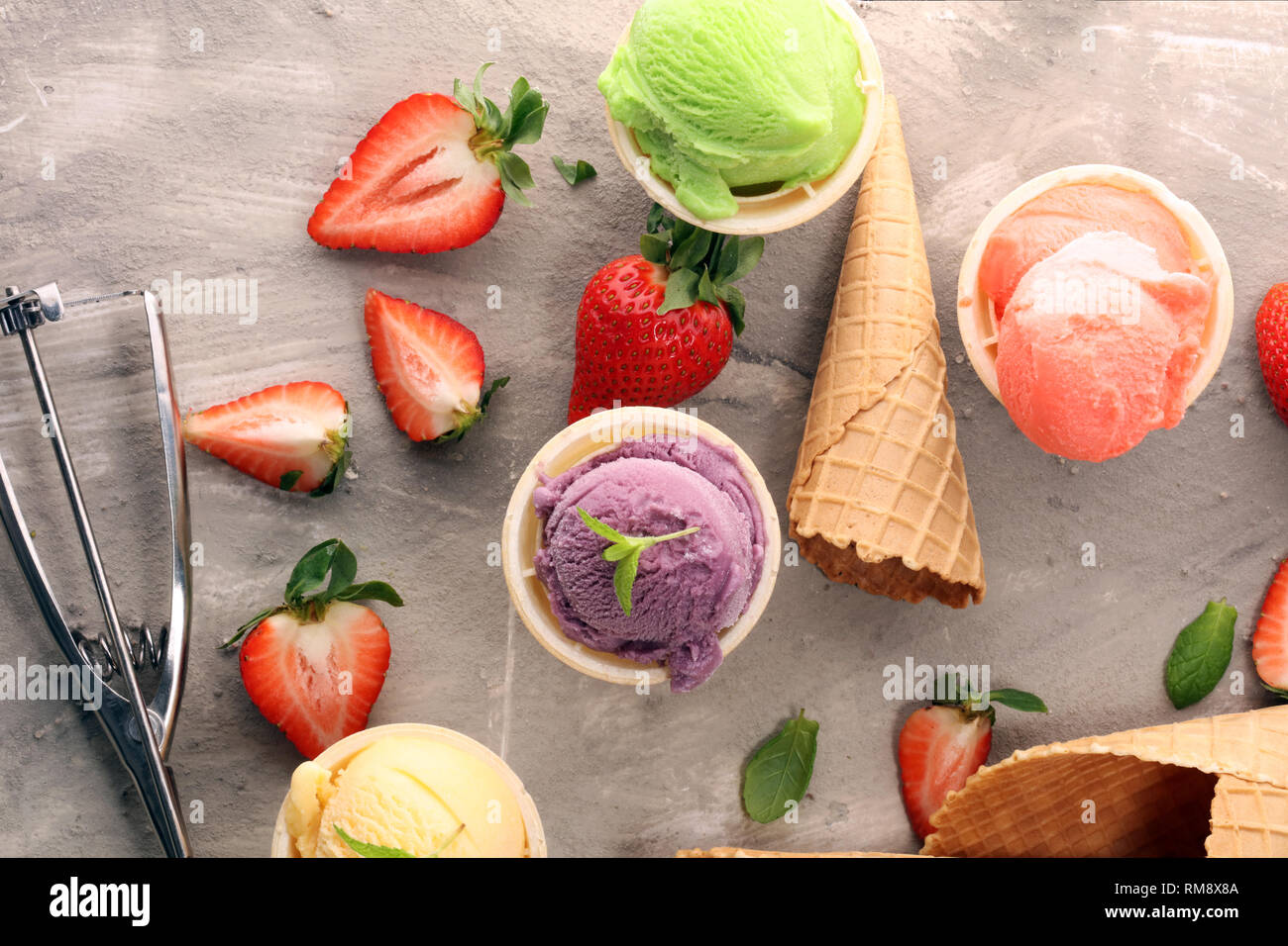 Set di gelato palline di diversi colori e sapori con frutti di bosco, menta e frutta Foto Stock