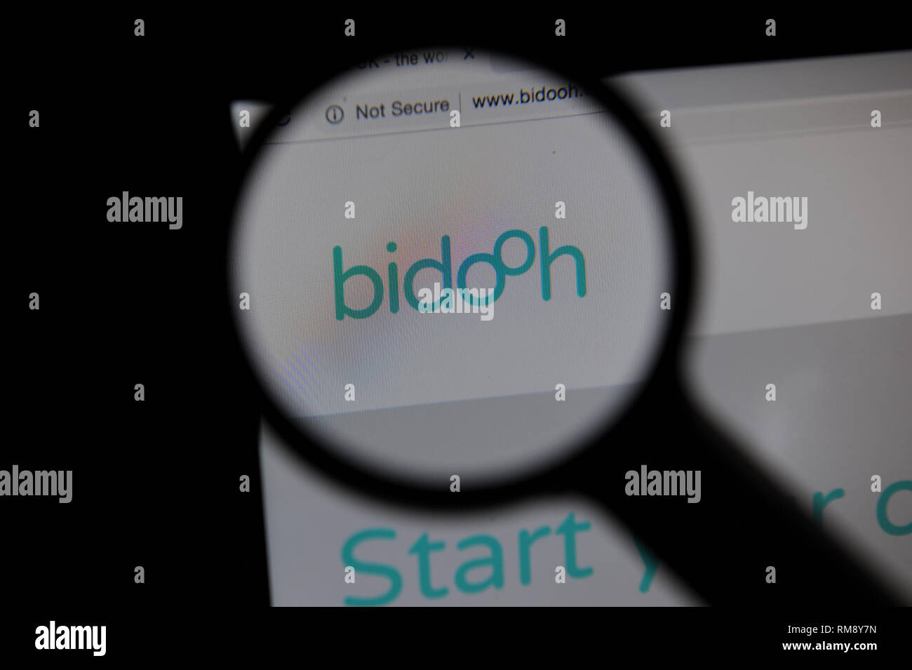 Sito web Bidooh visto attraverso una lente di ingrandimento sullo schermo di un computer Foto Stock