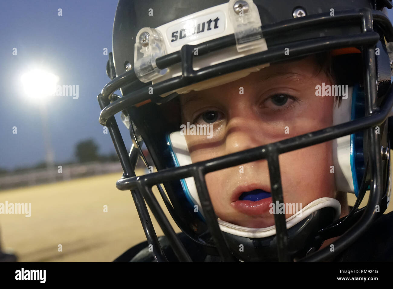 Una chiusura di un ragazzo che indossa un casco da football americano durante la pratica. Foto Stock