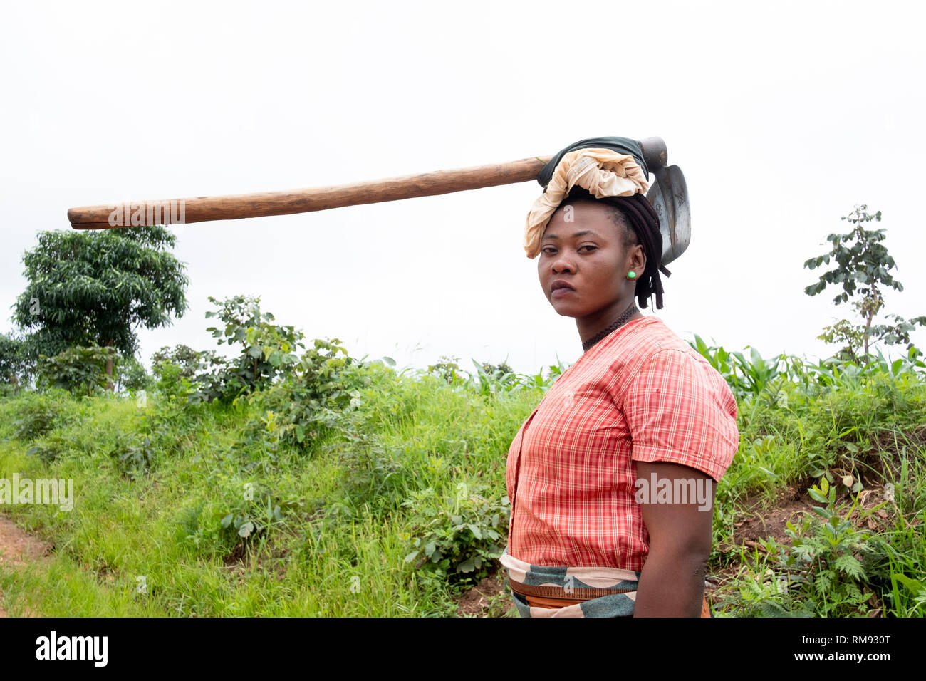 Un abitante di un villaggio porta una zappa sul suo capo come lei cammina home in Jubele, Dowa, Malawi Foto Stock