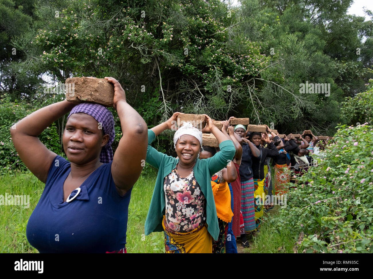 Le donne portano mattoni durante una processione per un funerale in Dowa, Malawi Foto Stock