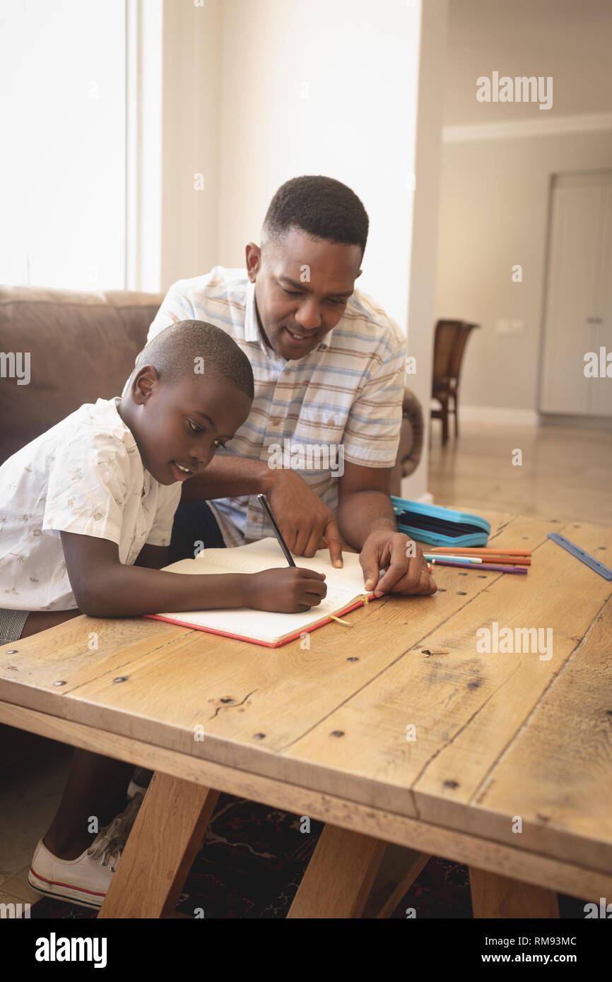 African American padre aiutando il suo figlio con i compiti a tavola Foto Stock