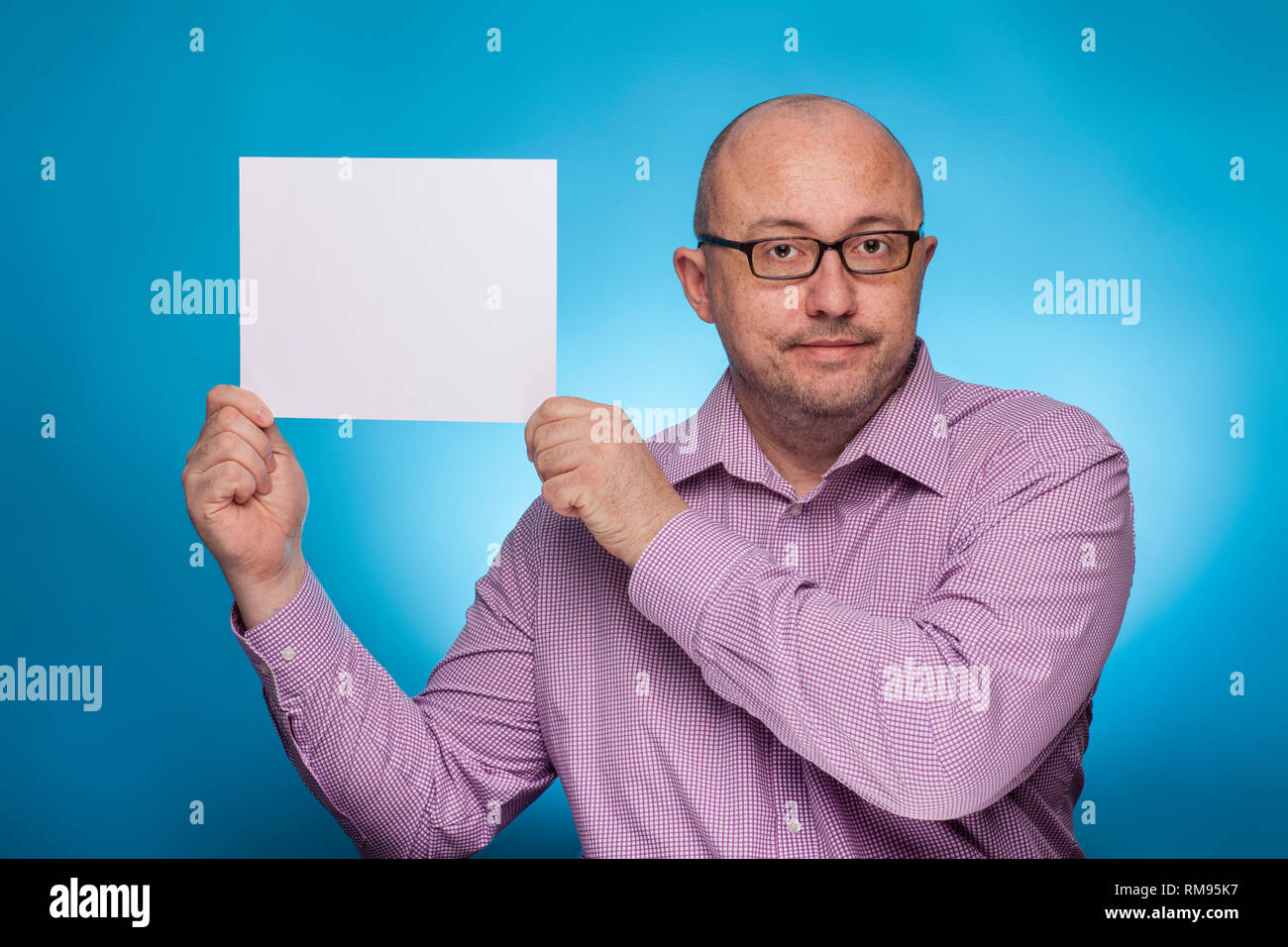Un imprenditore in un spinaroli shirt mantiene un vuoto, bianco segno, segnaposto, su sfondo blu. Foto Stock