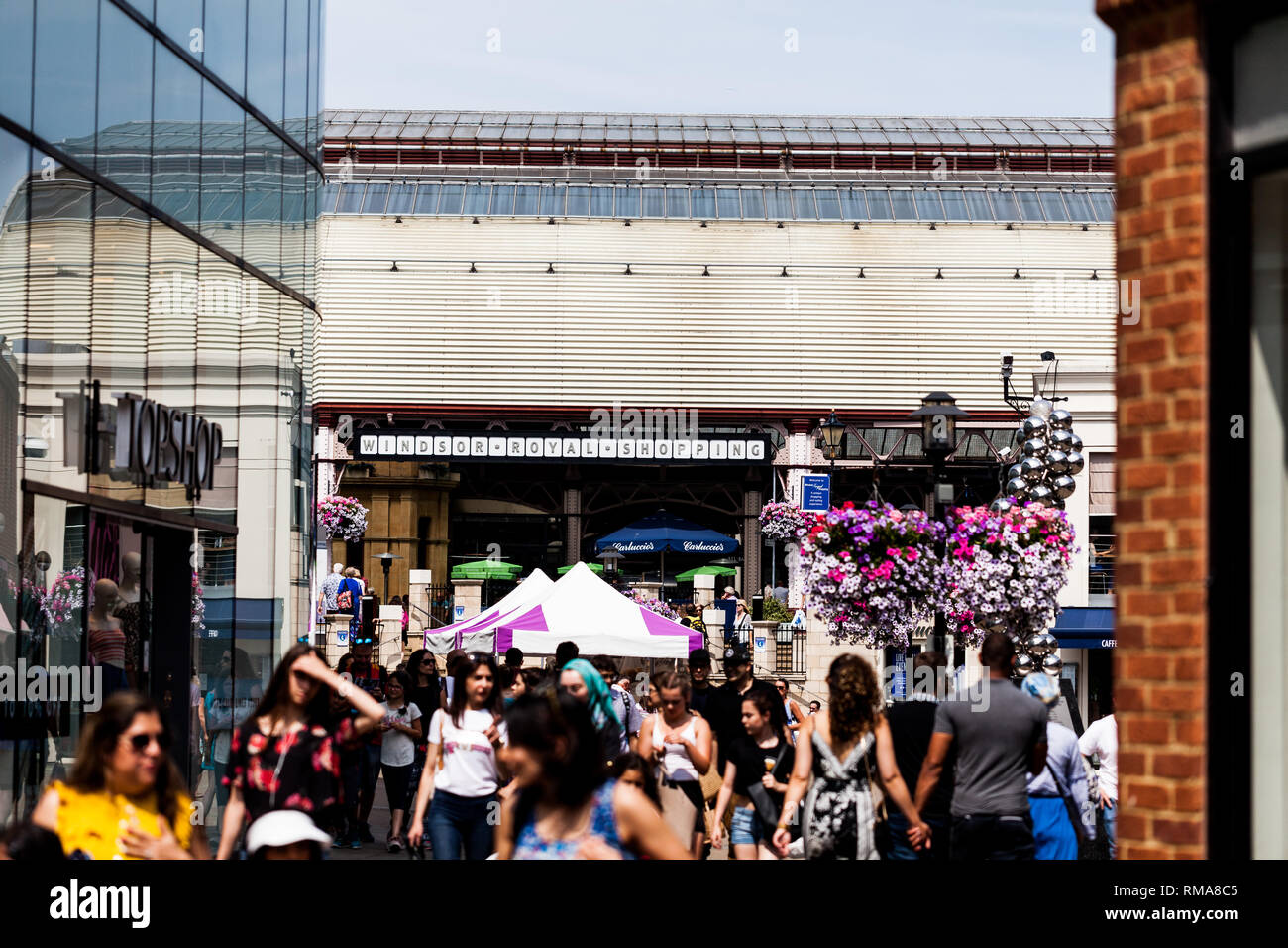 BIRMINGHAM, Regno Unito - Marzo 2018 Entrata a Eton Riverside Station e Windsor Royal Shopping. La gente camminare lungo la trafficata strada sulla giornata di sole. Facciata di edificio Foto Stock