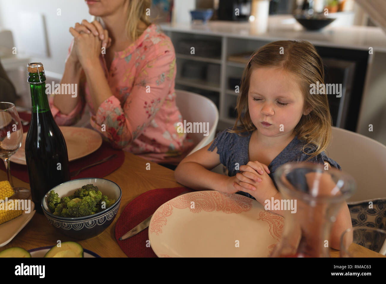Madre e figlia di pregare insieme prima di pasto Foto Stock