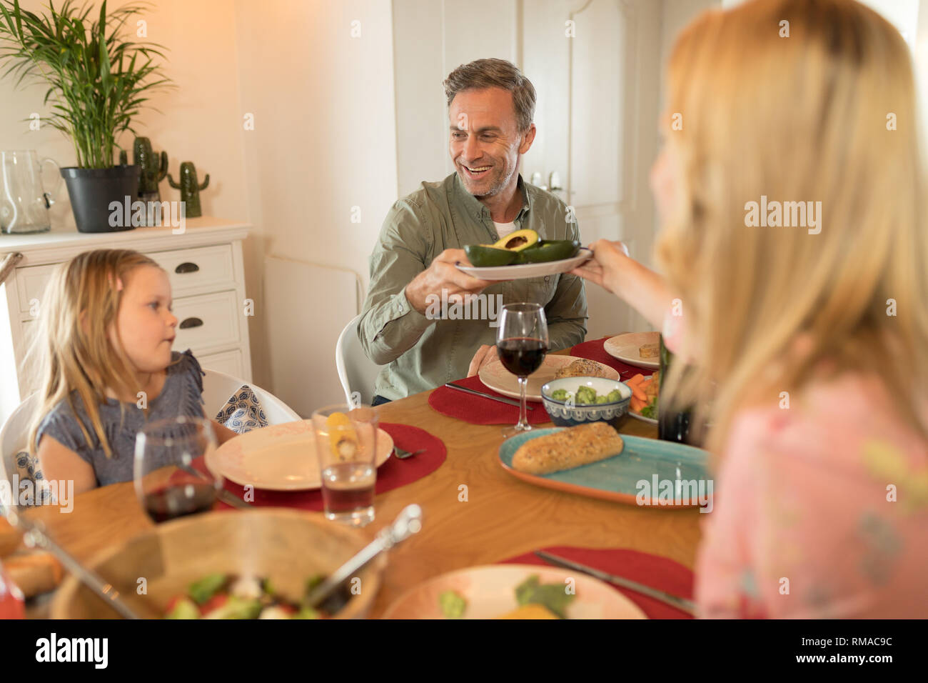 Donna passando il cibo per l'uomo sul tavolo da pranzo Foto Stock