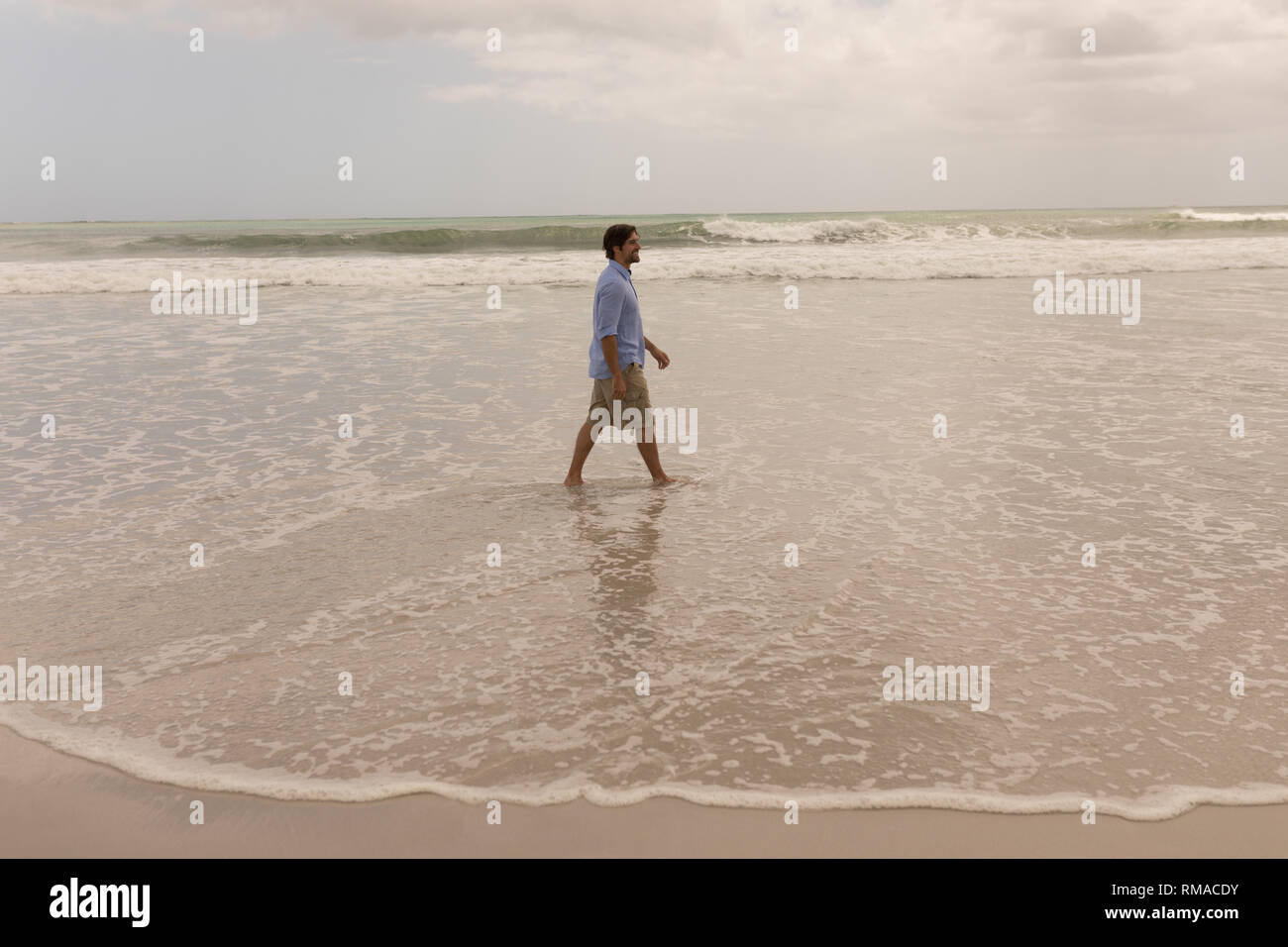 Vista laterale di un uomo a camminare sulla spiaggia Foto Stock