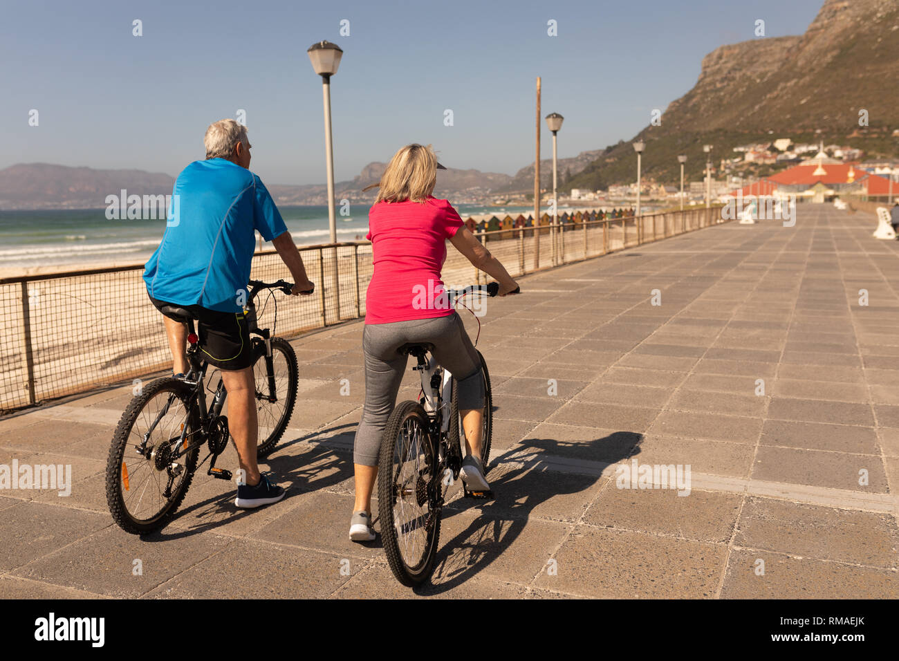 Coppia Senior in sella ad una bicicletta per una passeggiata in spiaggia Foto Stock