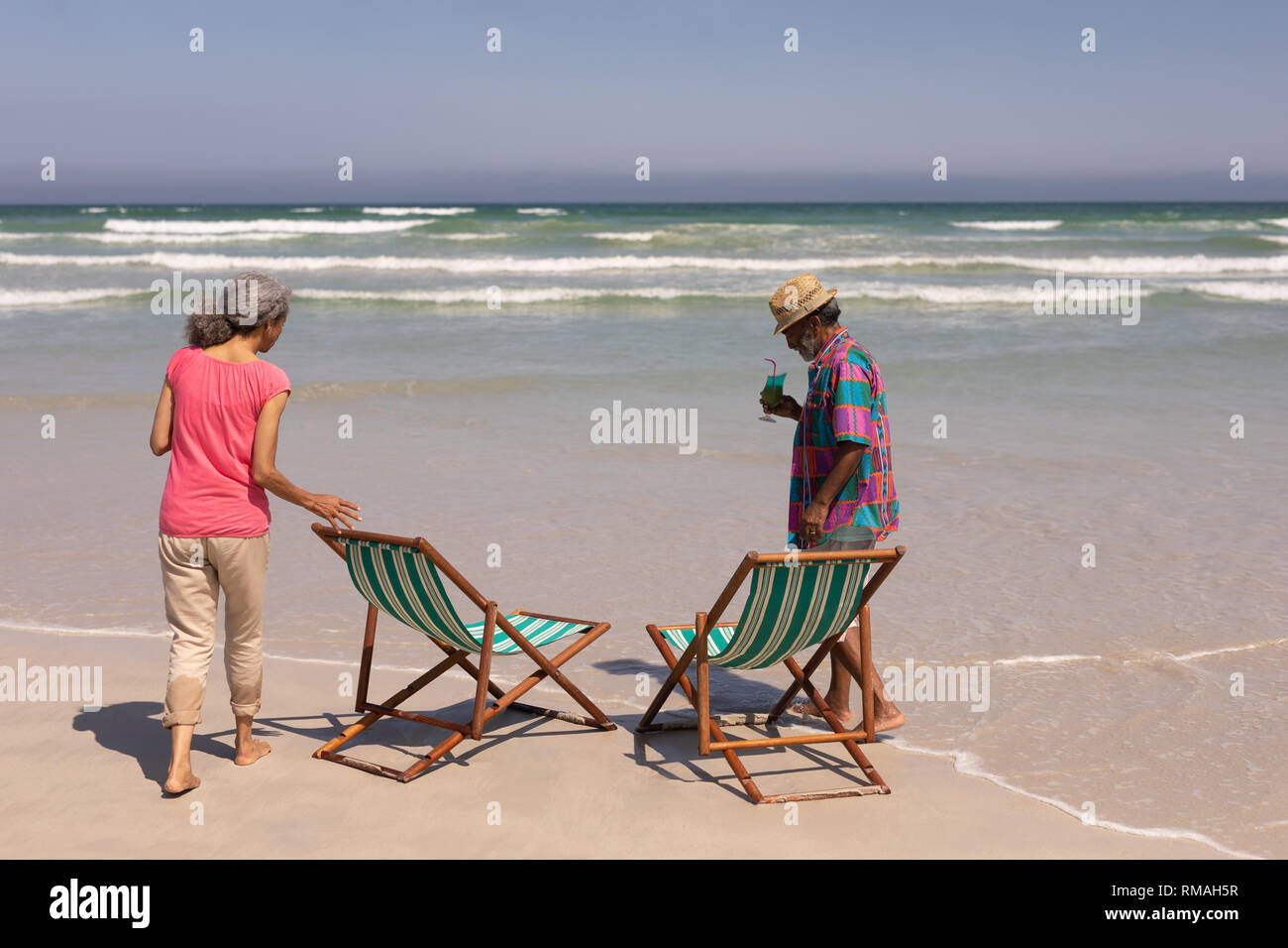 Coppia senior con lettini prendisole in piedi sulla spiaggia Foto stock -  Alamy