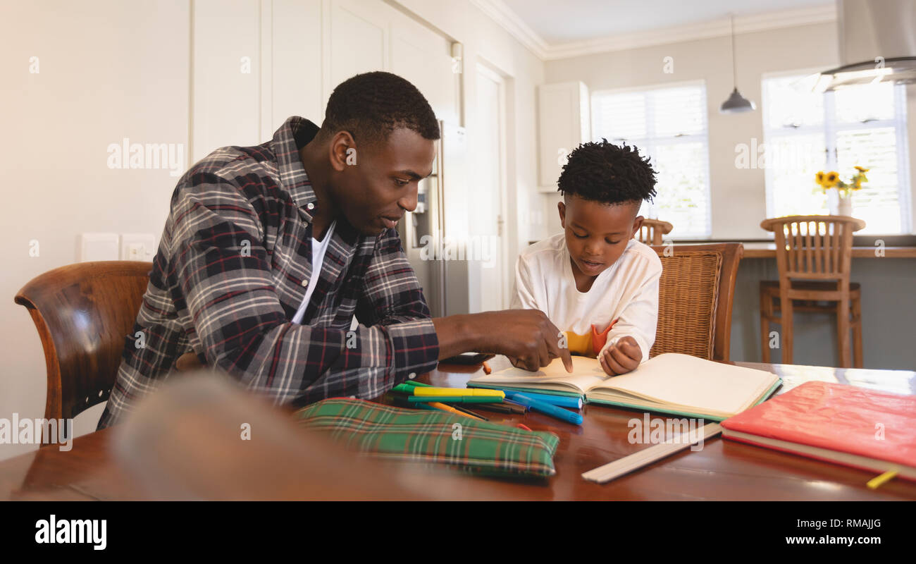 African American padre aiutando il suo figlio con i compiti a tavola Foto Stock