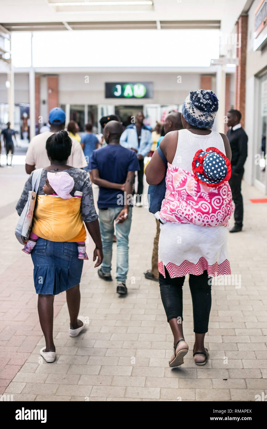 Johannesburg, Sud Africa - 4 settembre, 2018: mamme che trasportano i bambini sulle loro spalle. I neonati sono avvolti in un mantello fissato attorno la falena Foto Stock