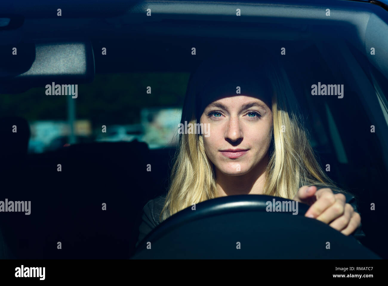 Vista frontale della giovane donna bionda sorridente mentre si guida auto Foto Stock