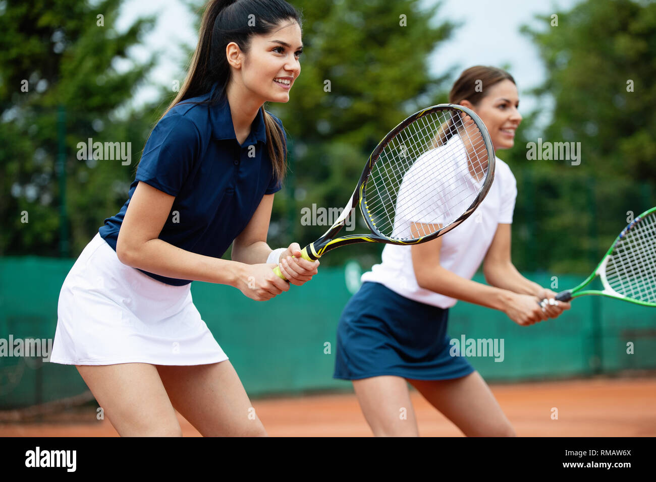 Giovani felici montare le donne giocare a tennis sul campo da tennis Foto Stock