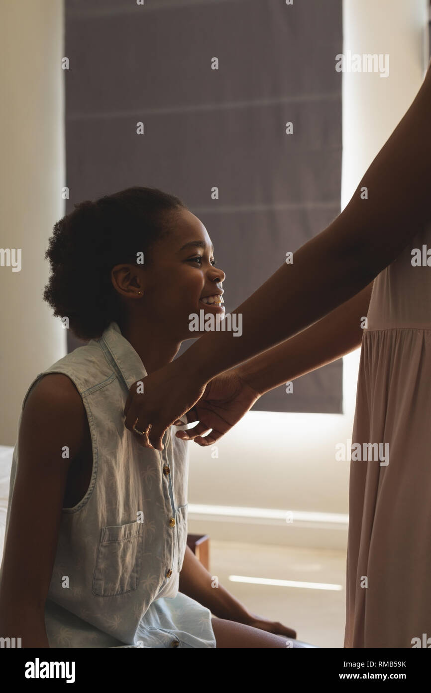 African American madre aiutando a sua figlia di indossare un panno in camera da letto Foto Stock