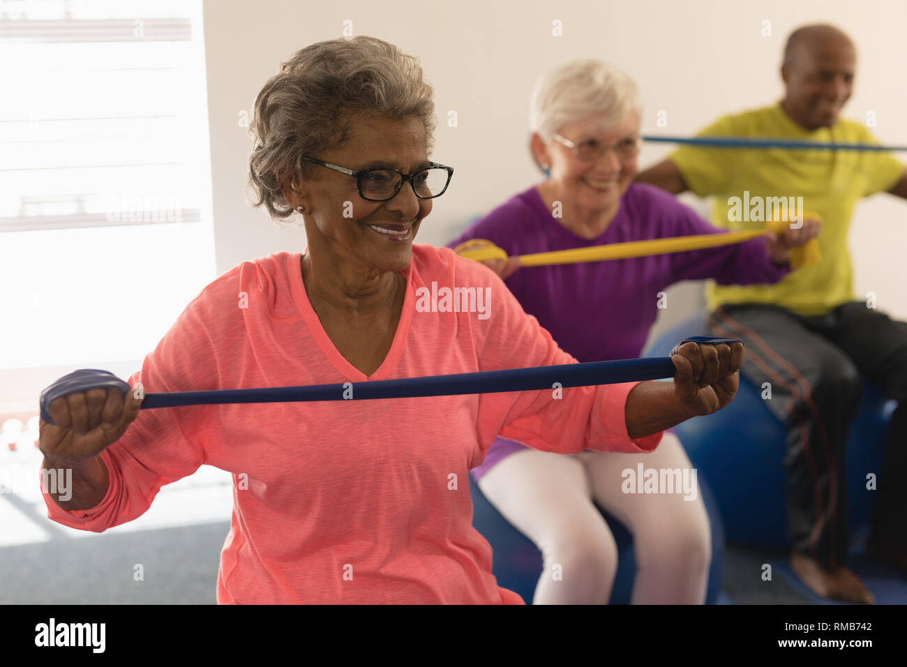 Senior donna esercitando con banda di resistenza in studio fitness Foto Stock