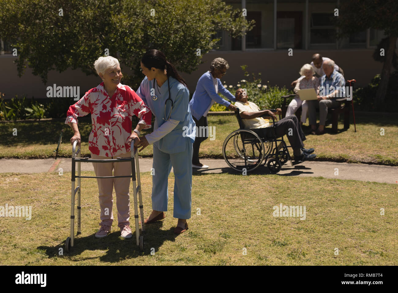 Giovani donne medico aiutare disabili donna senior in giardino Foto Stock
