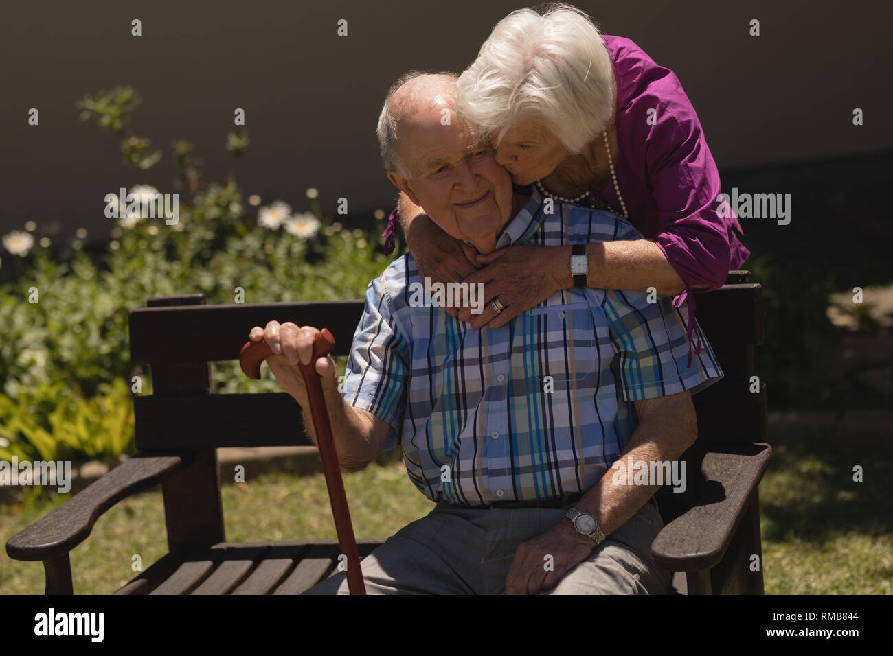 Senior donna abbracciando e baciando senior l uomo nel giardino Foto Stock
