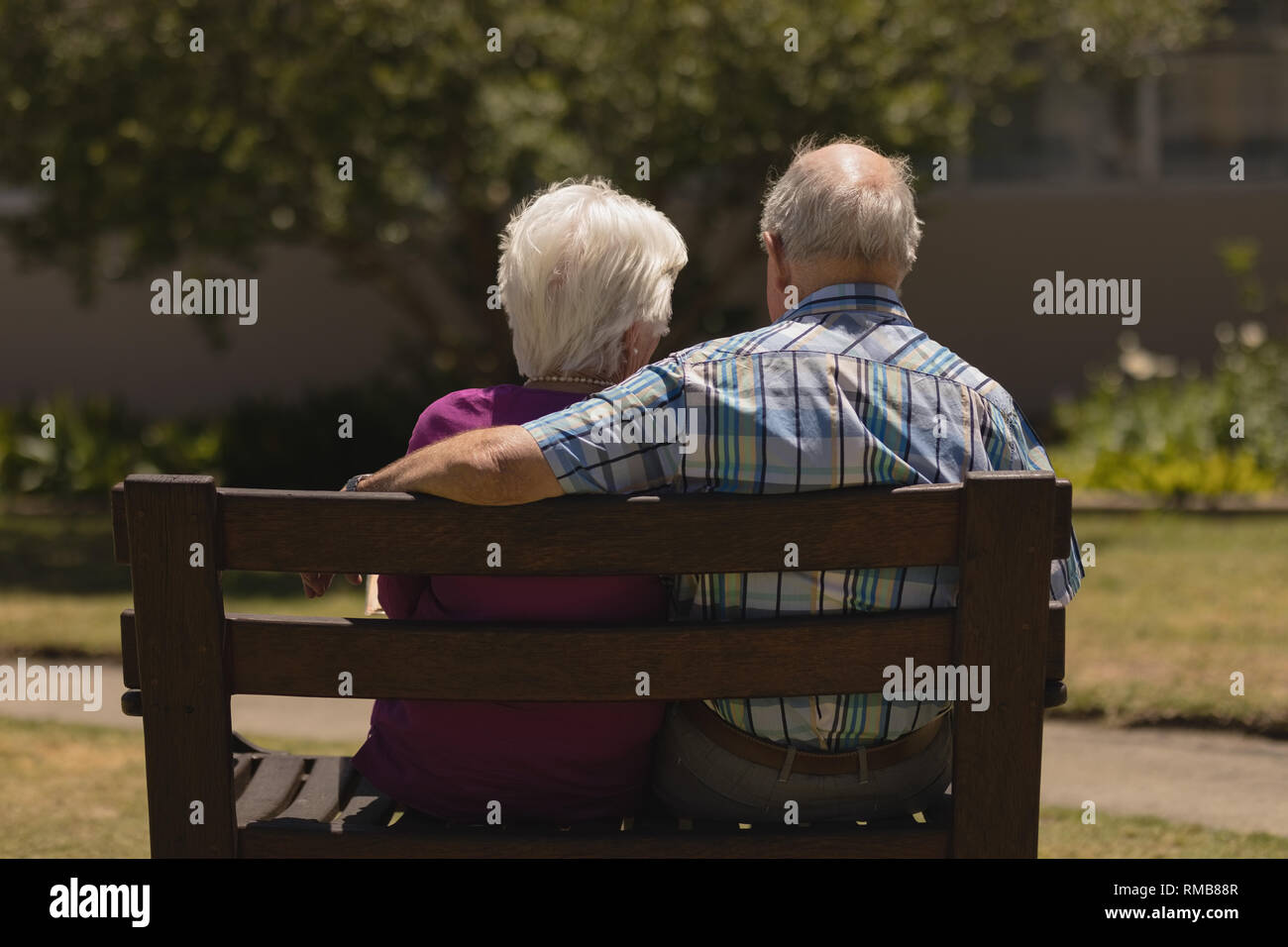 Coppia senior seduti insieme sulla panchina nel parco Foto Stock