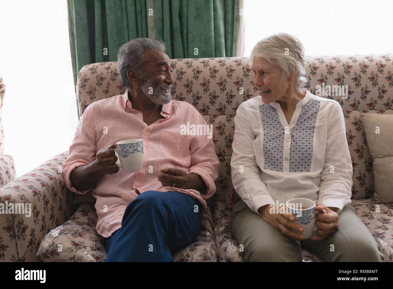 Coppia senior interagire gli uni con gli altri mentre un caffè nella stanza vivente Foto Stock