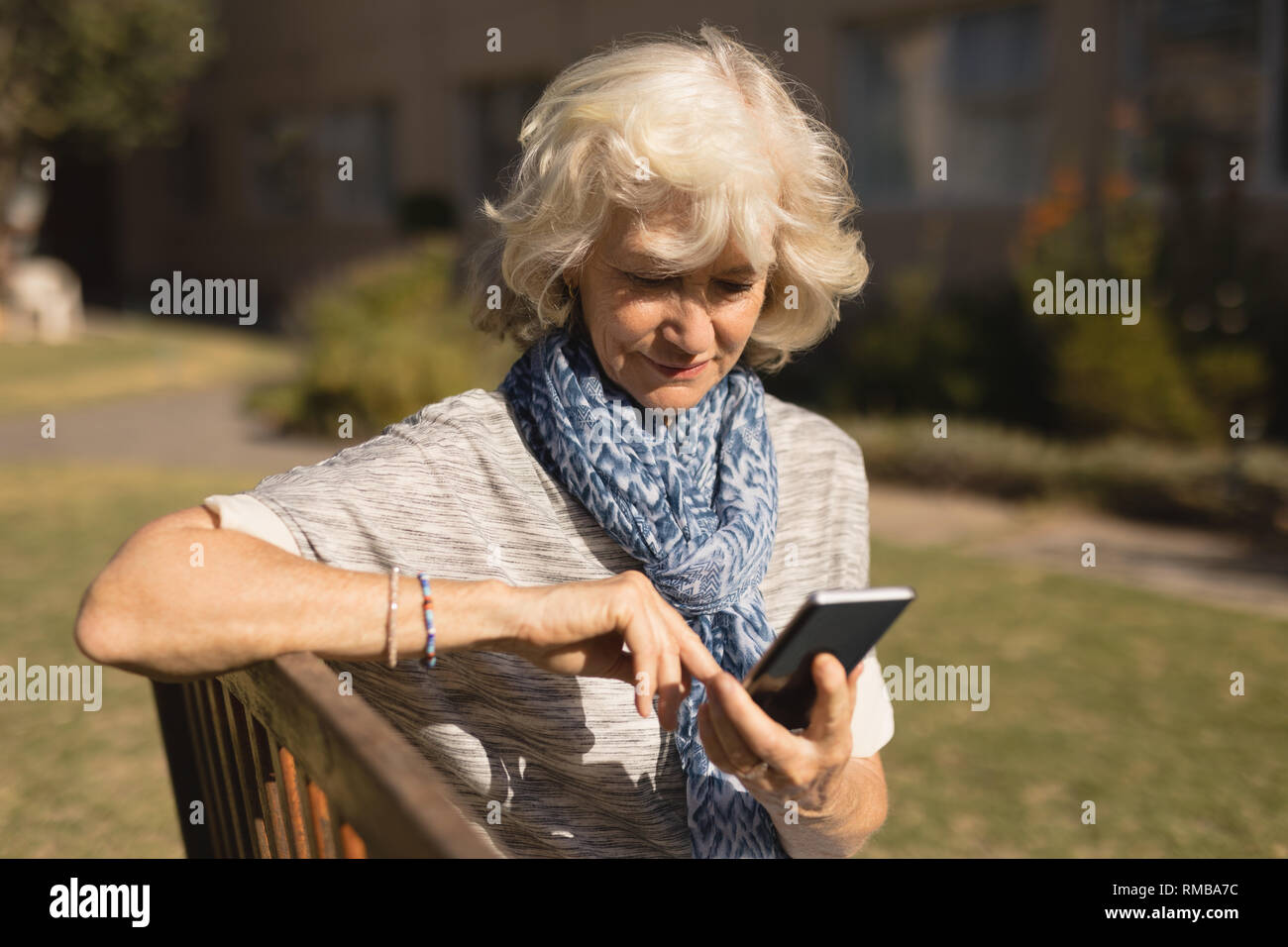 Senior donna utilizzando il telefono cellulare nel parco Foto Stock