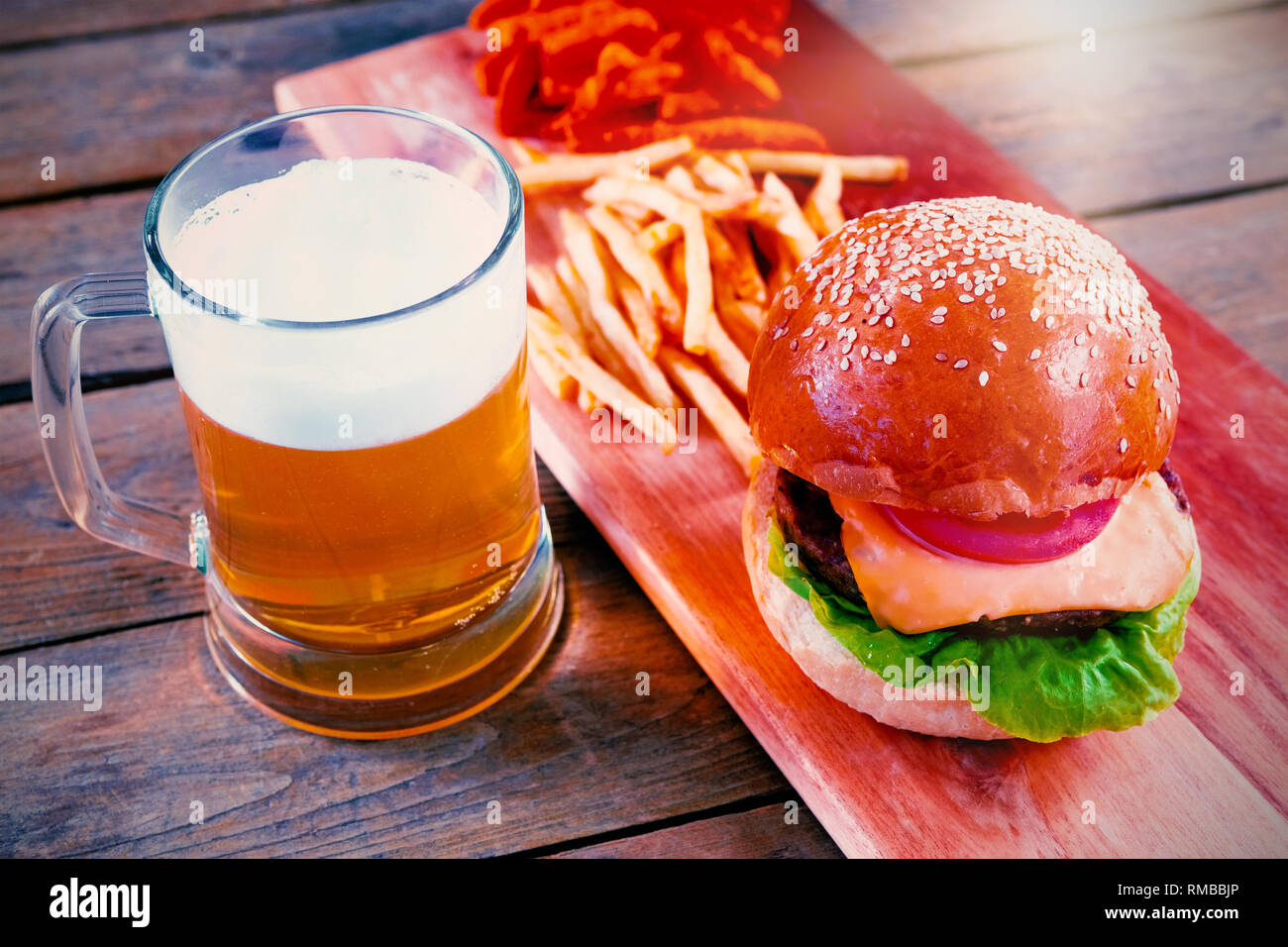 Boccale di birra, hamburger e patatine sul tavolo di legno Foto Stock