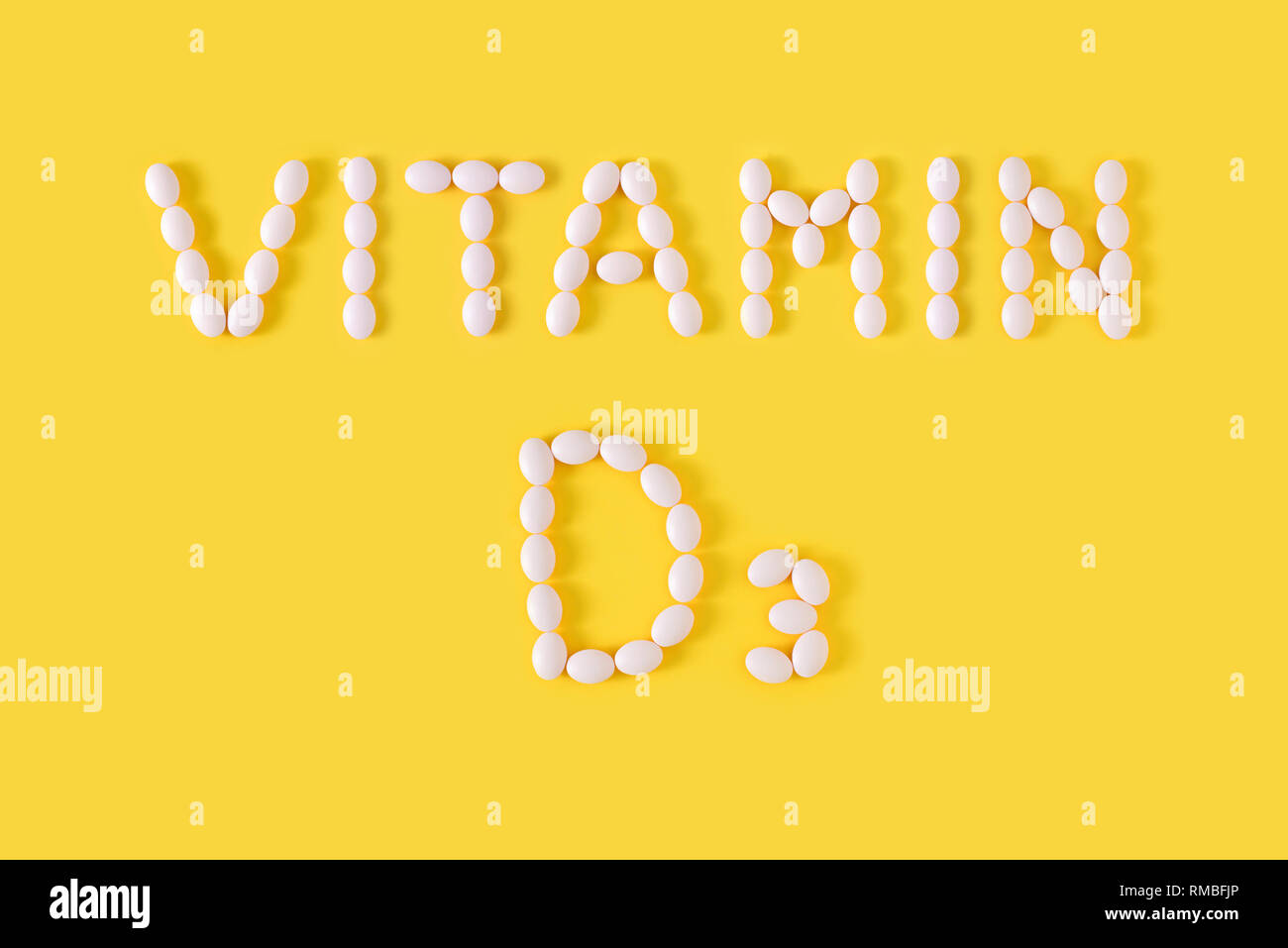 La vitamina D3 pillole sceso dalla bottiglia su sfondo giallo. Appartamento laico, vista dall'alto, copia gratuita dello spazio. Foto Stock