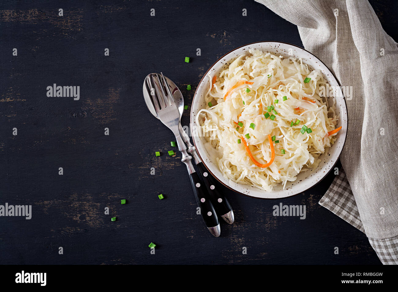 Cavolo fermentato. Cibo vegan. Crauti con la carota e spezie in ciotola su sfondo scuro. Cibo di tendenza. Vista superiore . Appartamento laici, spazio di copia Foto Stock