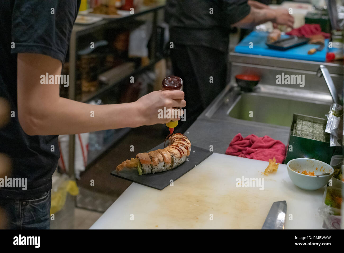 Le mani di asiatici gli chef cucinare il sushi e la cucina giapponese, rendendo il sushi roll e decorare Foto Stock