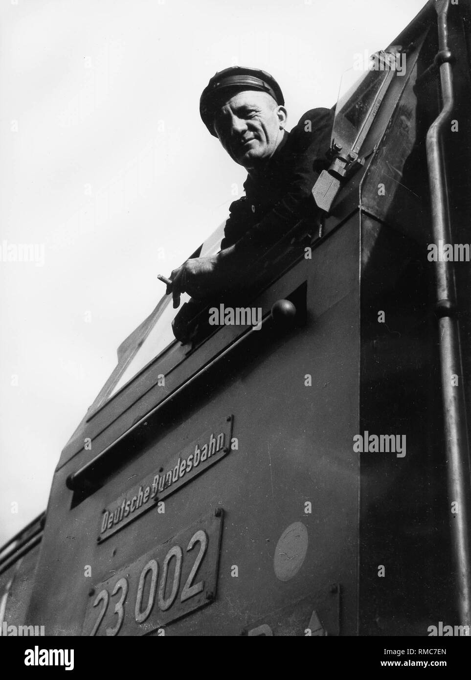 Un macchinista guarda fuori della cabina di un locomotore. Foto Stock