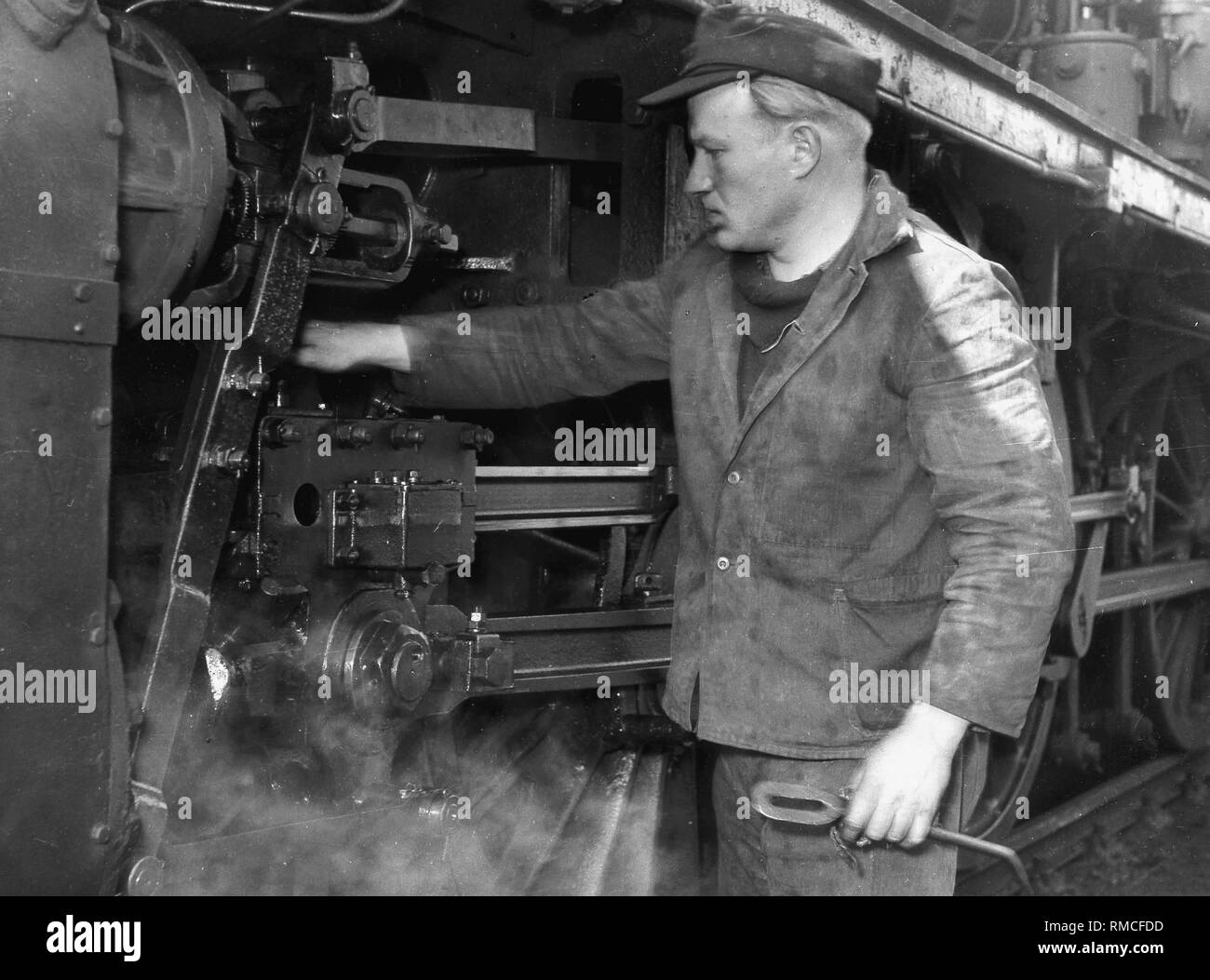 I lavoratori che operano su una locomotiva a vapore nel negozio di riparazioni a Lindau stazione ferroviaria. Foto Stock