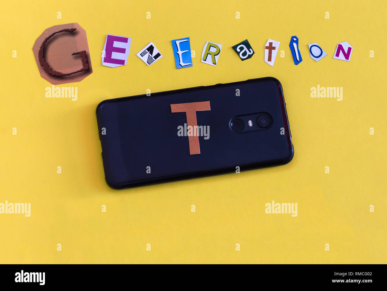 La parola 'Generazione T' formate con le lettere tagliate e un smarthphone. La tecnologia di nuova generazione dopo la millenaria chiamato anche la generazione di alfa. Foto Stock