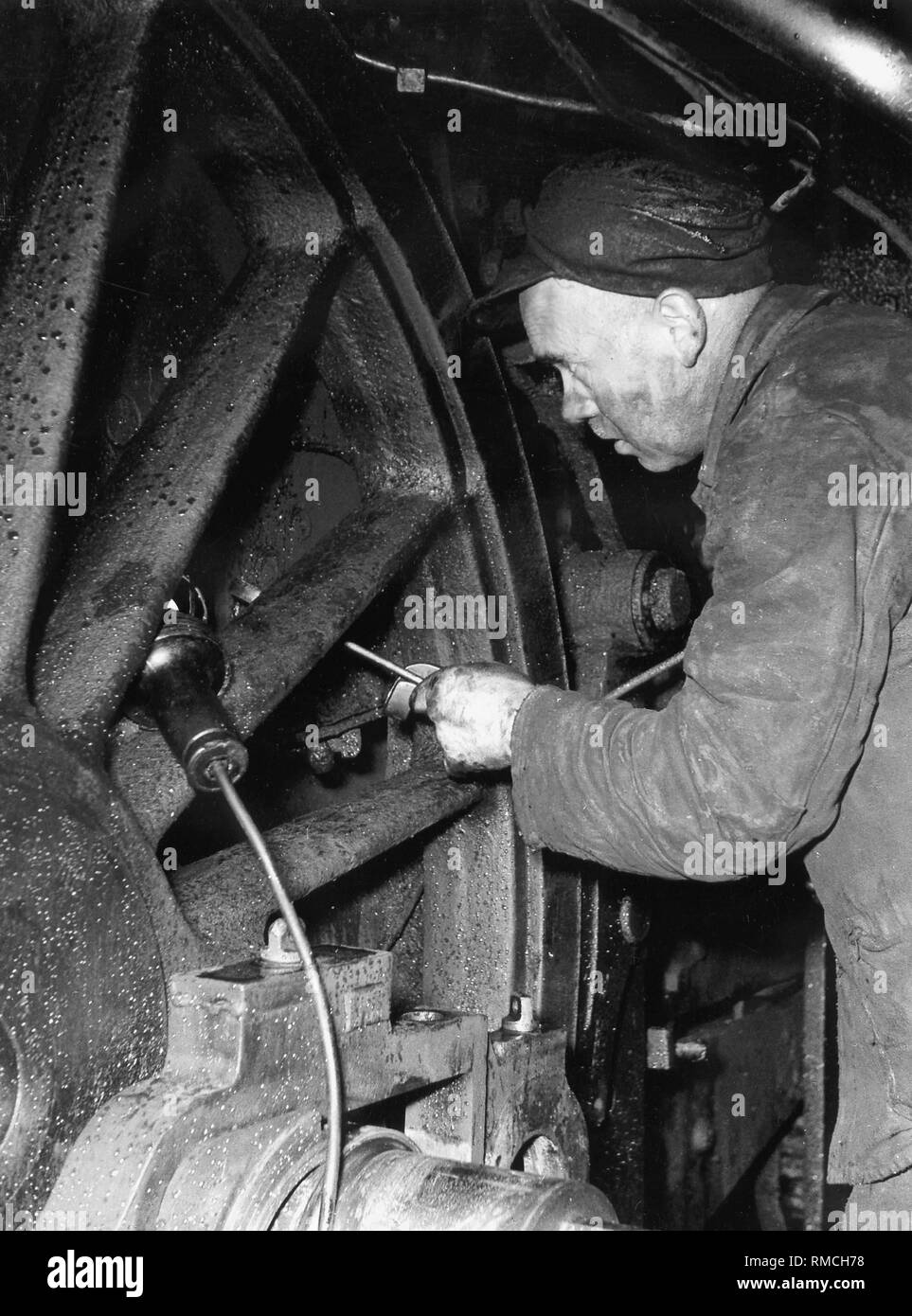 I lavoratori che operano su una locomotiva a vapore nel negozio di riparazioni a Lindau stazione ferroviaria. Foto Stock