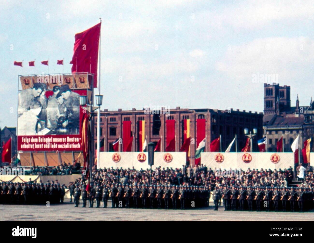 Unità di vari rami della RDT Esercito del popolo presso la parata militare del 1 maggio 1959 sull'Marx-Engels-Platz a Berlino Est e sullo sfondo la costruzione della Bauakademie che fu demolita nel 1962, proprio accanto, la rovina della chiesa Friedrichswerderschen. Foto Stock