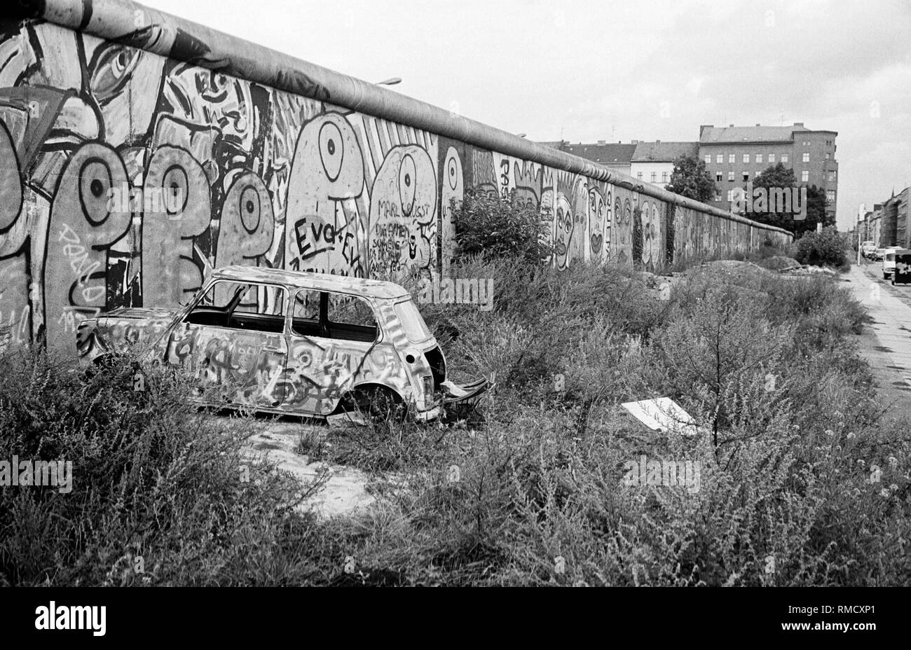 Il muro di Berlino il Waldemarstrasse nel quartiere Kreuzberg. La cosiddetta area di base è spesso usato in Occidente i berlinesi come discarica. Questa zona è di circa due metri di ampia striscia di terra su questo lato della parete che appartiene a Berlino Est. Foto Stock